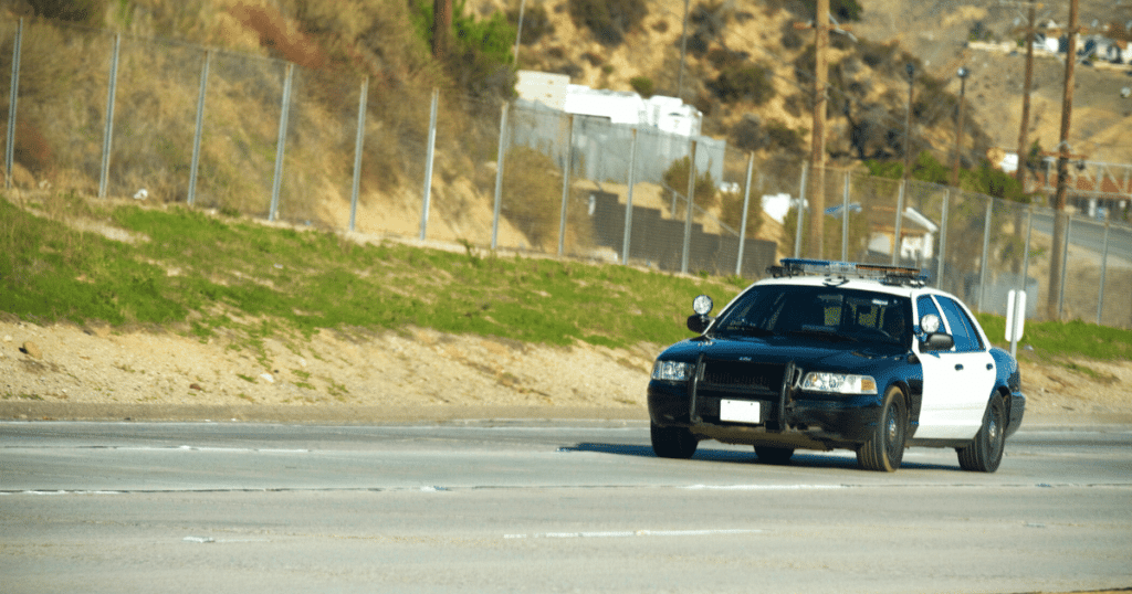 Police Car Driving on Road in Daylight