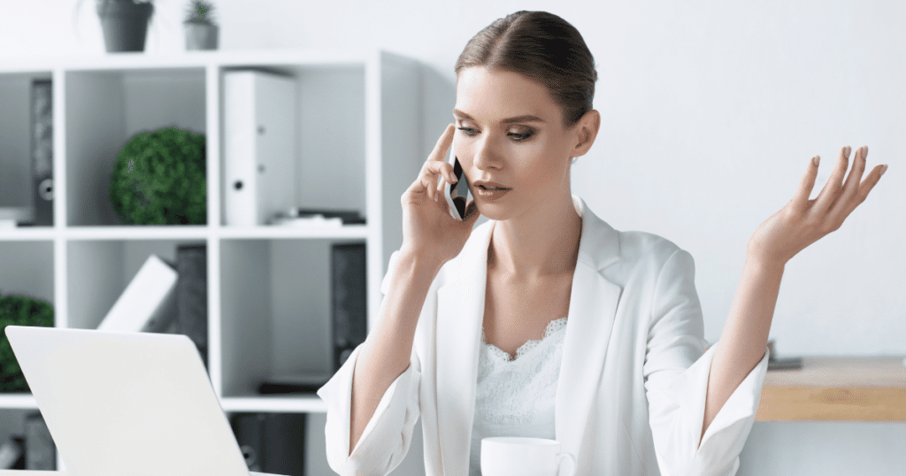 Woman Talking on Smartphone While Looking at Laptop